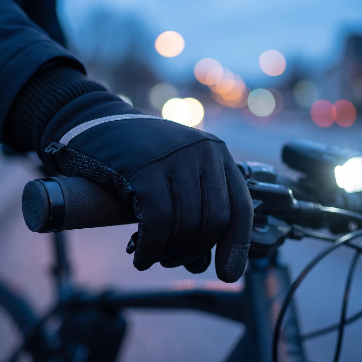 Hand im Dämmer-Handschuh am Lenkergriff, Griffmuster und Reflektorstreifen in der Abenddämmerung