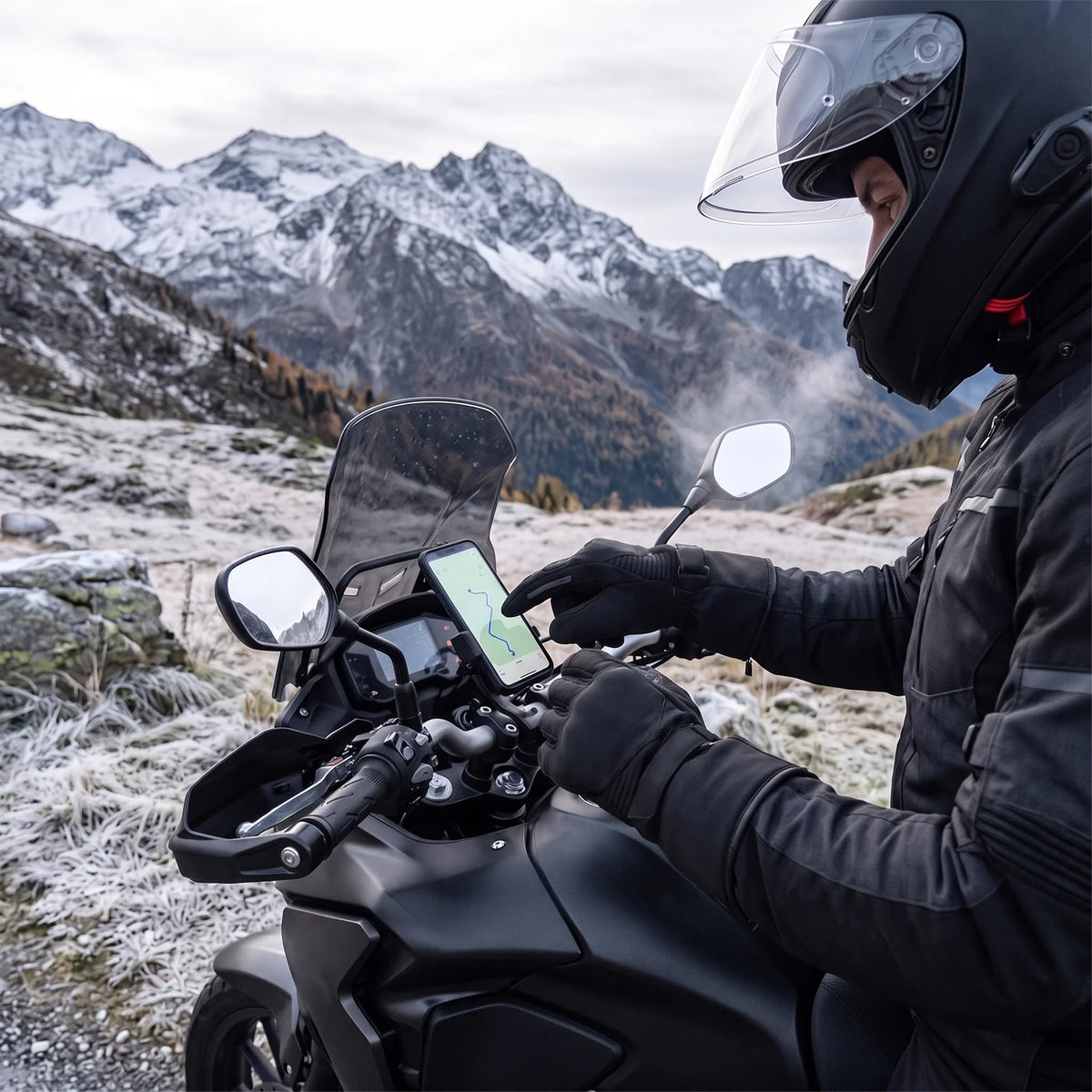Motorradfahrer tippt mit Handschuh auf das Navi am Lenker, Alpenpass im Herbst